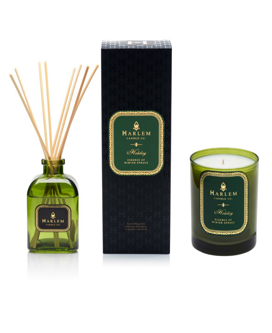 Our 8 fluid oz. Holiday Reed Diffuser with reeds, in a green glass vessel next to a green Holiday 11oz candle. sitting on a white background.