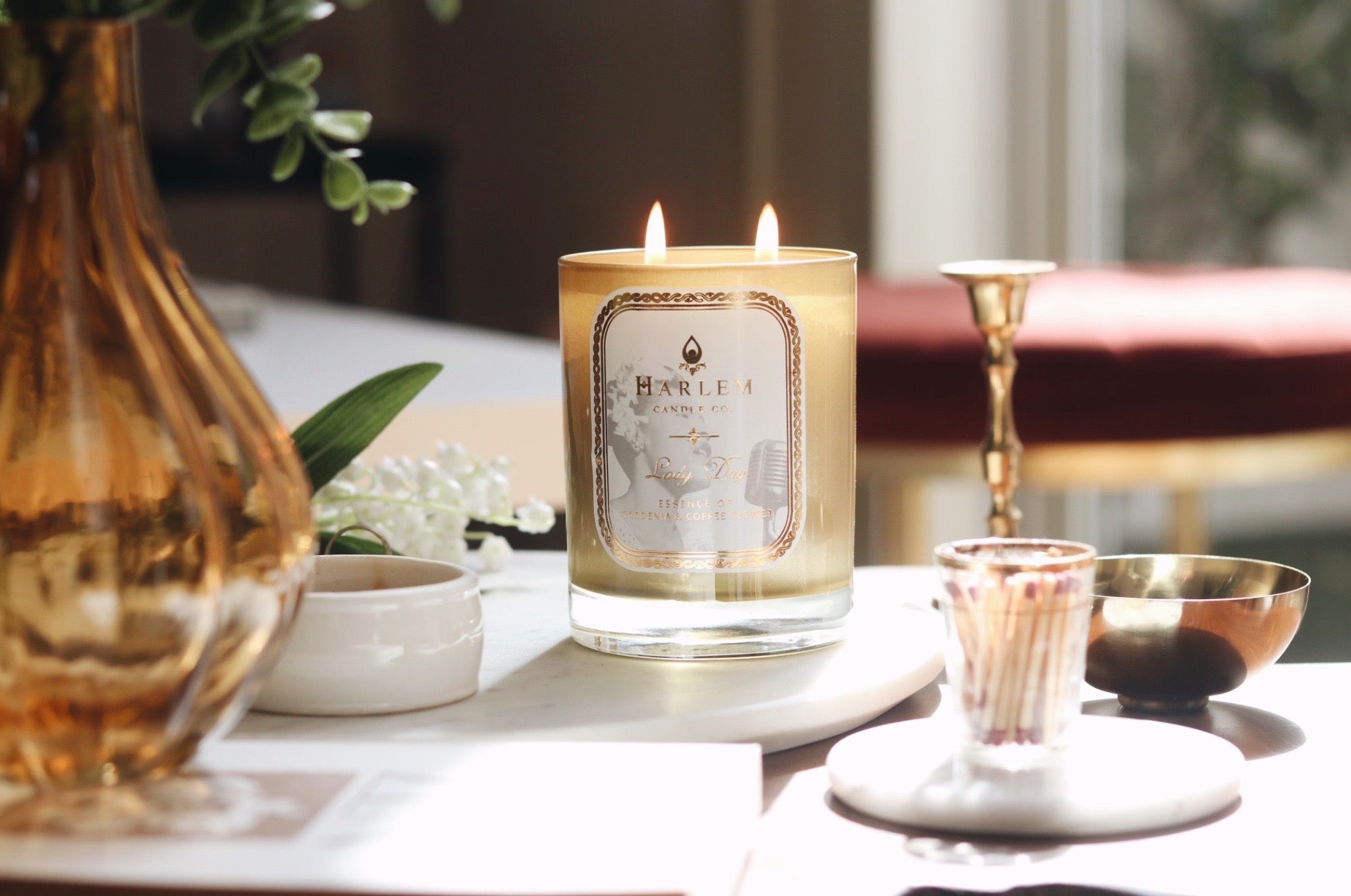 Lifestyle image of the Lady Day candle on a beautiful table with flowers.