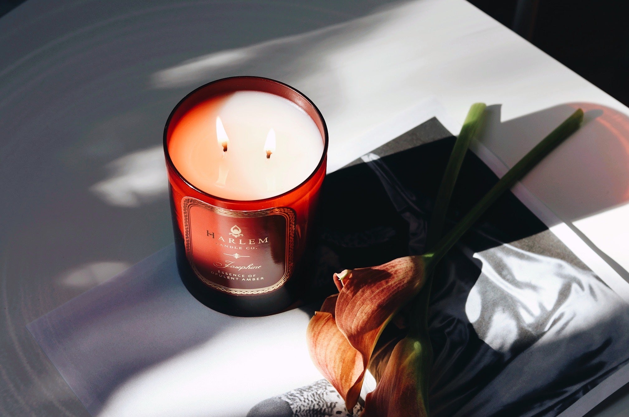 This is a lifestyle image of our Josephine candle illuminated next to flowers