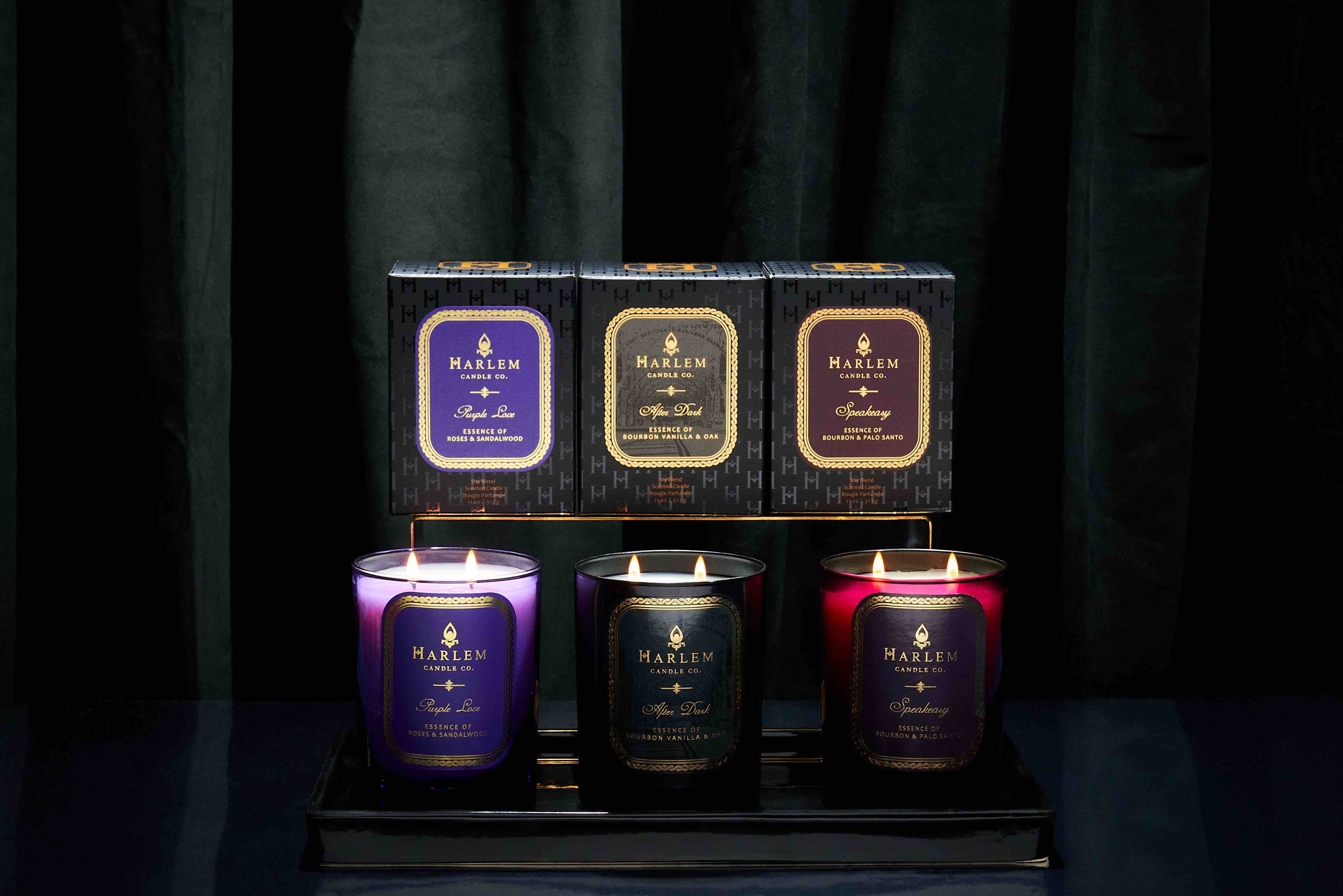This is an image of the Purple Love, Speakeasy and After Dark Candle Gift Box featured  ona black table with curtains behind them.