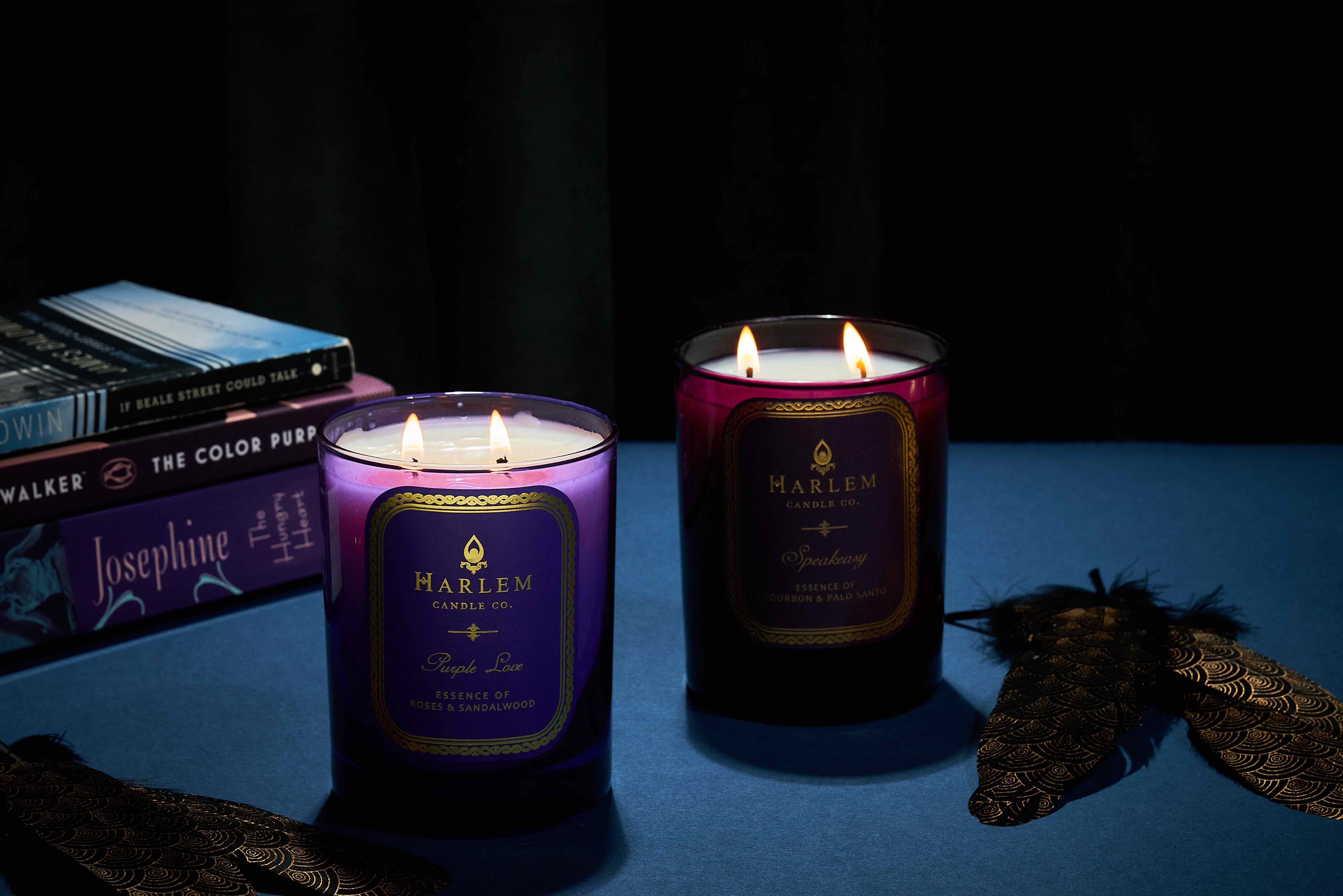 This is an image of our Speakeasy and Purple Love candle bundle on a blue table with books behind.
