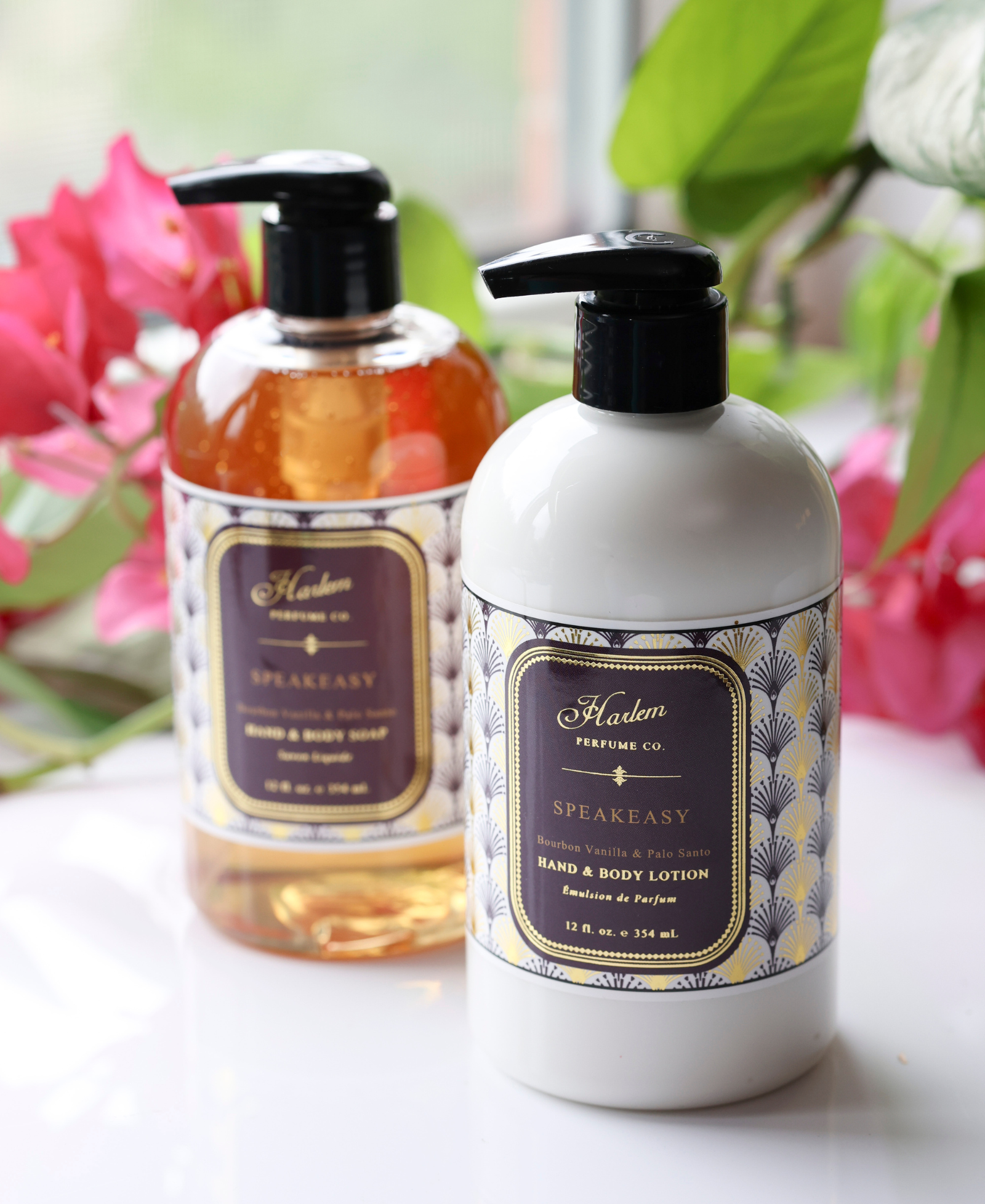This is an image of our Speakeasy Soap and Lotion pictured next to pink flowers. The bottles have a black pump and the labels have a unique Art Deco print with the details of both the soap and the lotion.