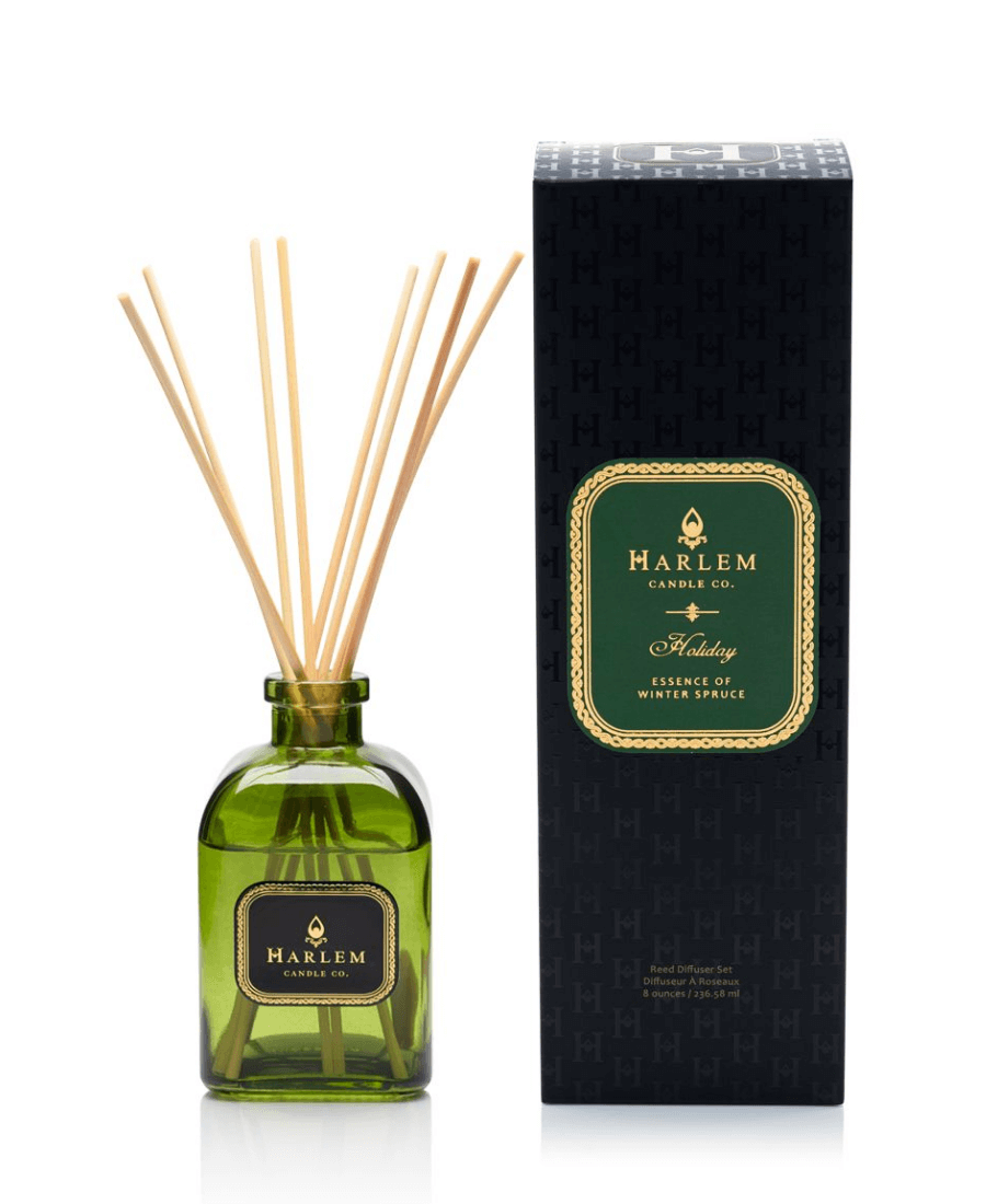 Our 8 fluid oz. Holiday Reed Diffuser with reeds, in a green glass vessel sitting next to its decorative box on a white background.