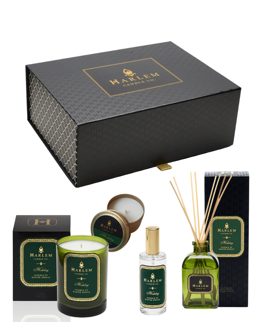 Our gorgeous custom Harlem Candle Co black gift box with the H pattern with theimages of our Holiday 12 oz 1 wick candle, our 4 oz Holiday Travel Tin, our 4 fl oz Holiday Room spray and our green glass Holiday Reed Diffuser sitting next to its decorative box.