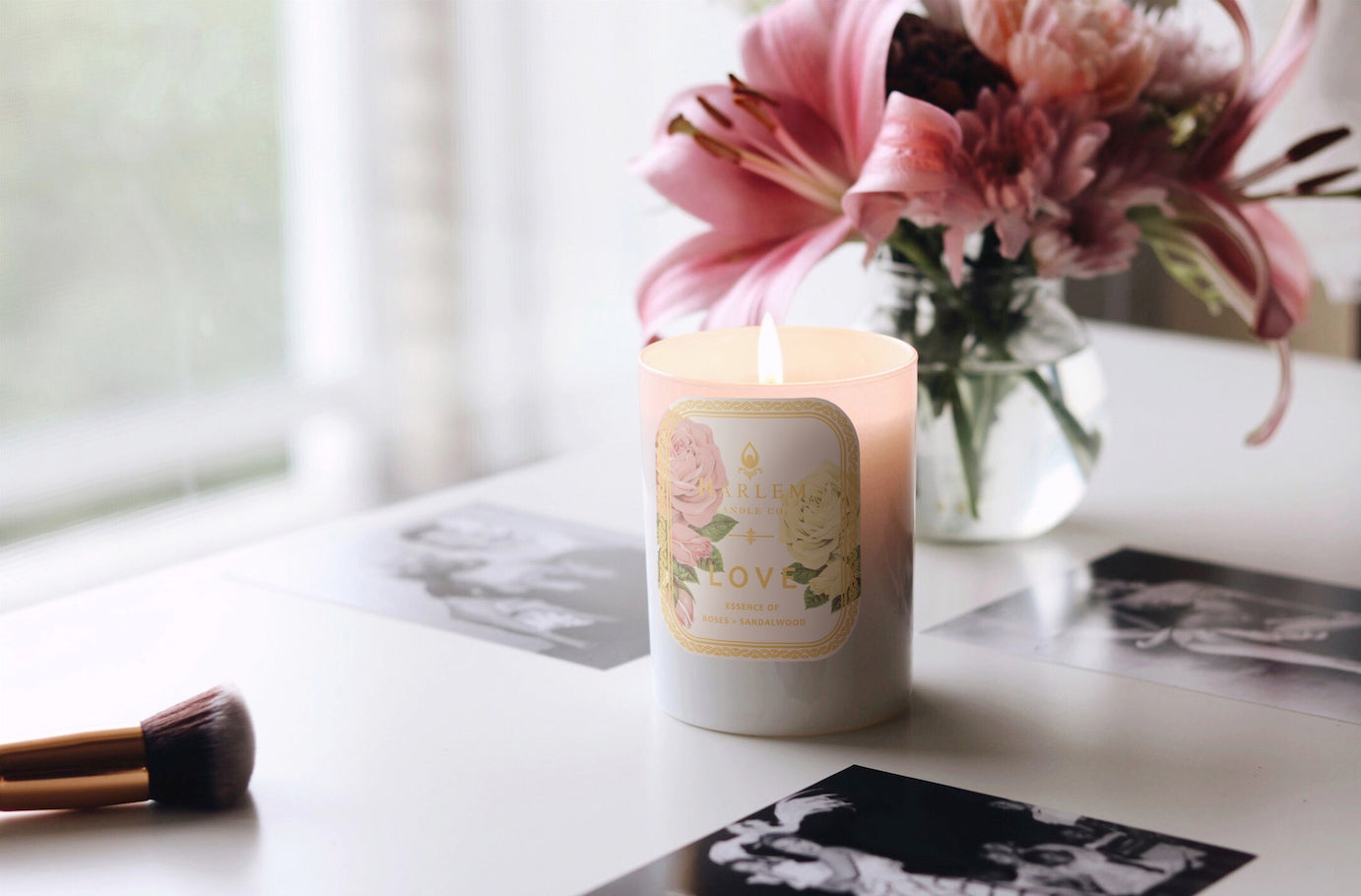 Lifestyle image of our Love botanical candle with flowers and a makeup brush